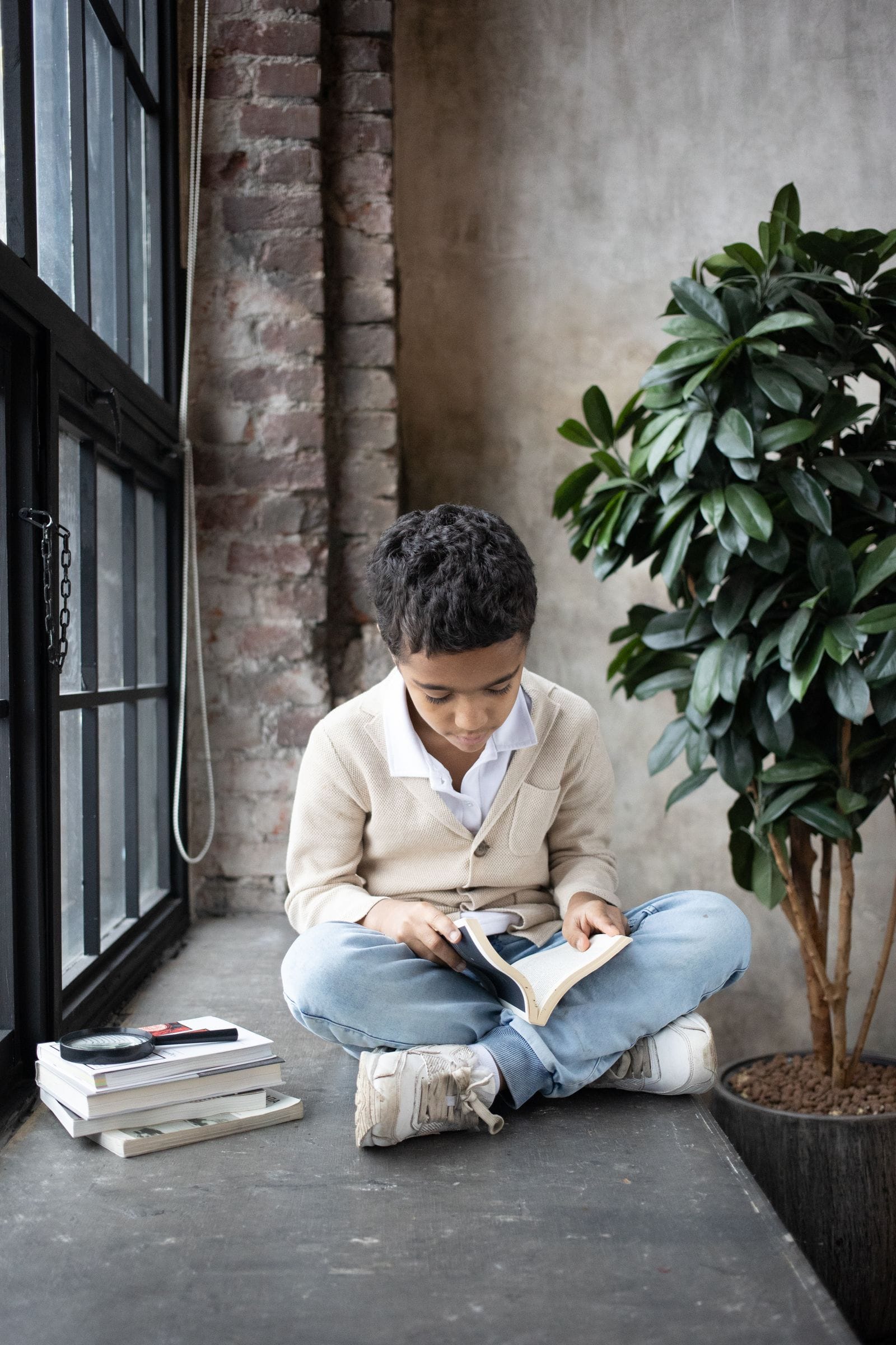 Niño leyendo un libro sentado junto a la ventana